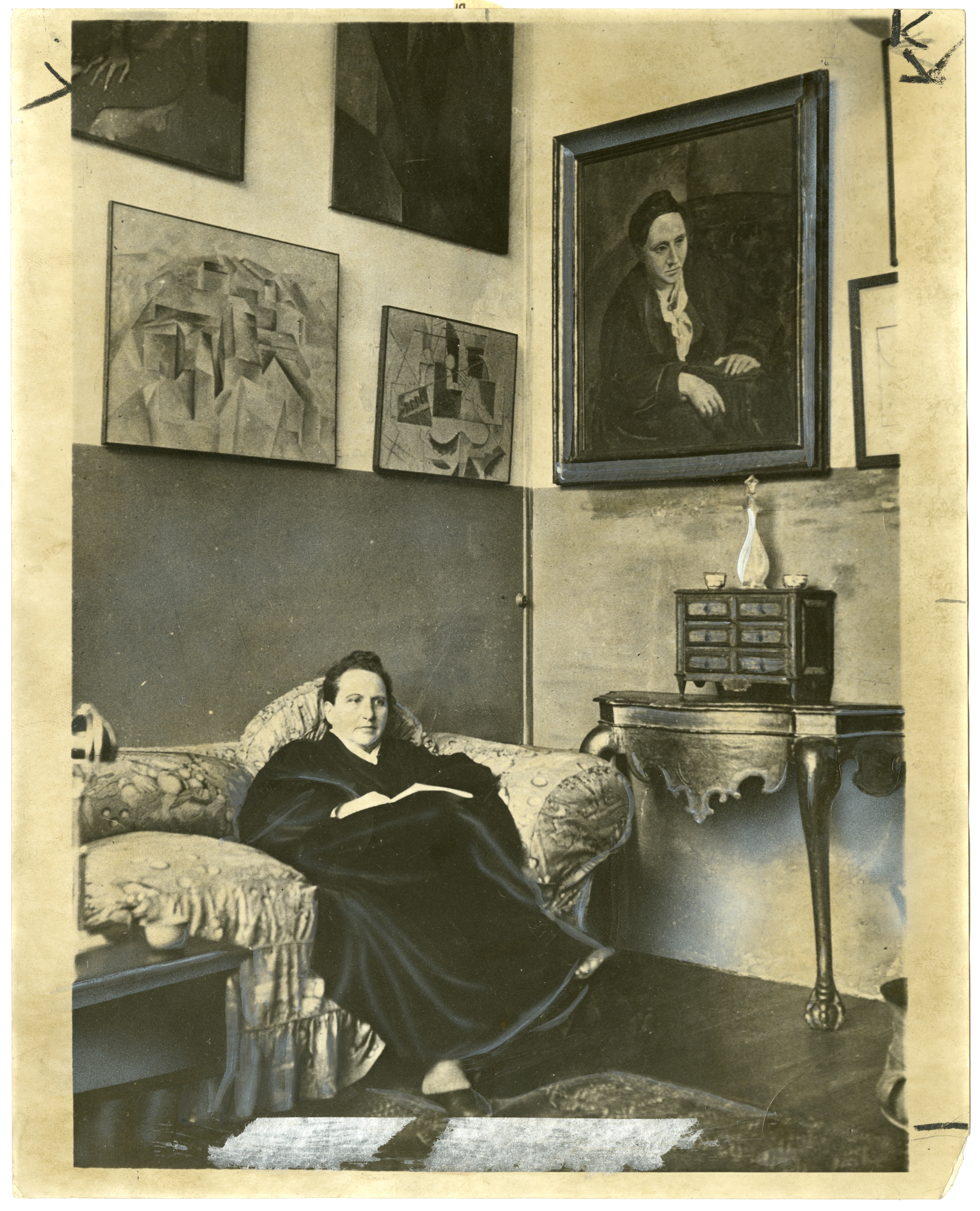 Gertrude Stein at home under her portrait by Picasso, who is a character in "Twenty-Seven."