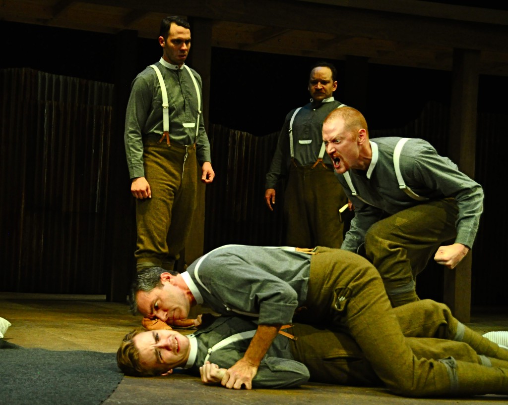 A suspected Catholic, Martin Crawford (Dylan Marquis Meyers) is assaulted by fellow soldier Nat McIlwaine (Tony Bingham) while fellow agitator George Anderson (Jonathan Visser) spurs the attack. In the background William Moore (Byron Anthony, left) and Christopher Roulston (Justin R. G. Holcolmb, right) look on.