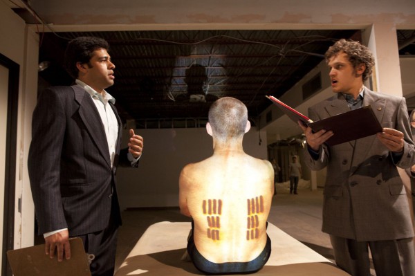 What do the tattoos signify?  Scholars (Anand Nagraj, left, and Antonio Marziale) expound their views while the Iceman (Malcolm Tulip) displays the evidence.  