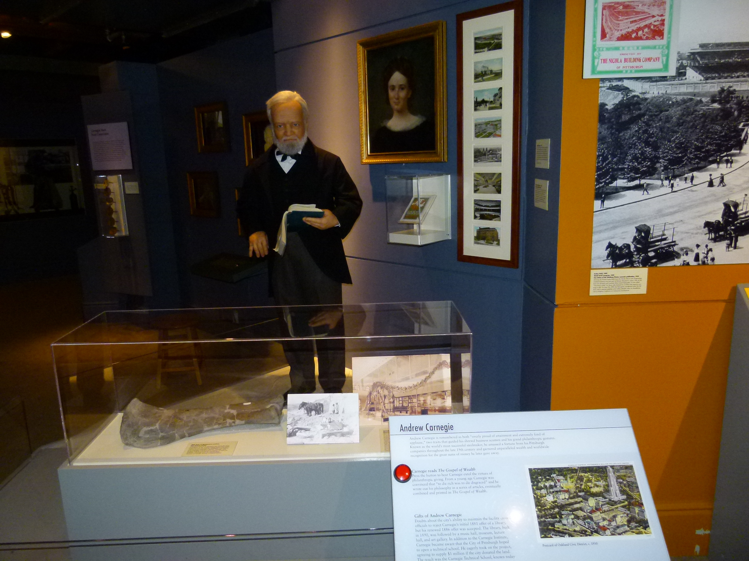 Pittsburgh industrialist Andrew Carnegie standing behind a dinosaur bone he funded the discovery of, and holding a book to signify his creation of Carnegie free Libraries.