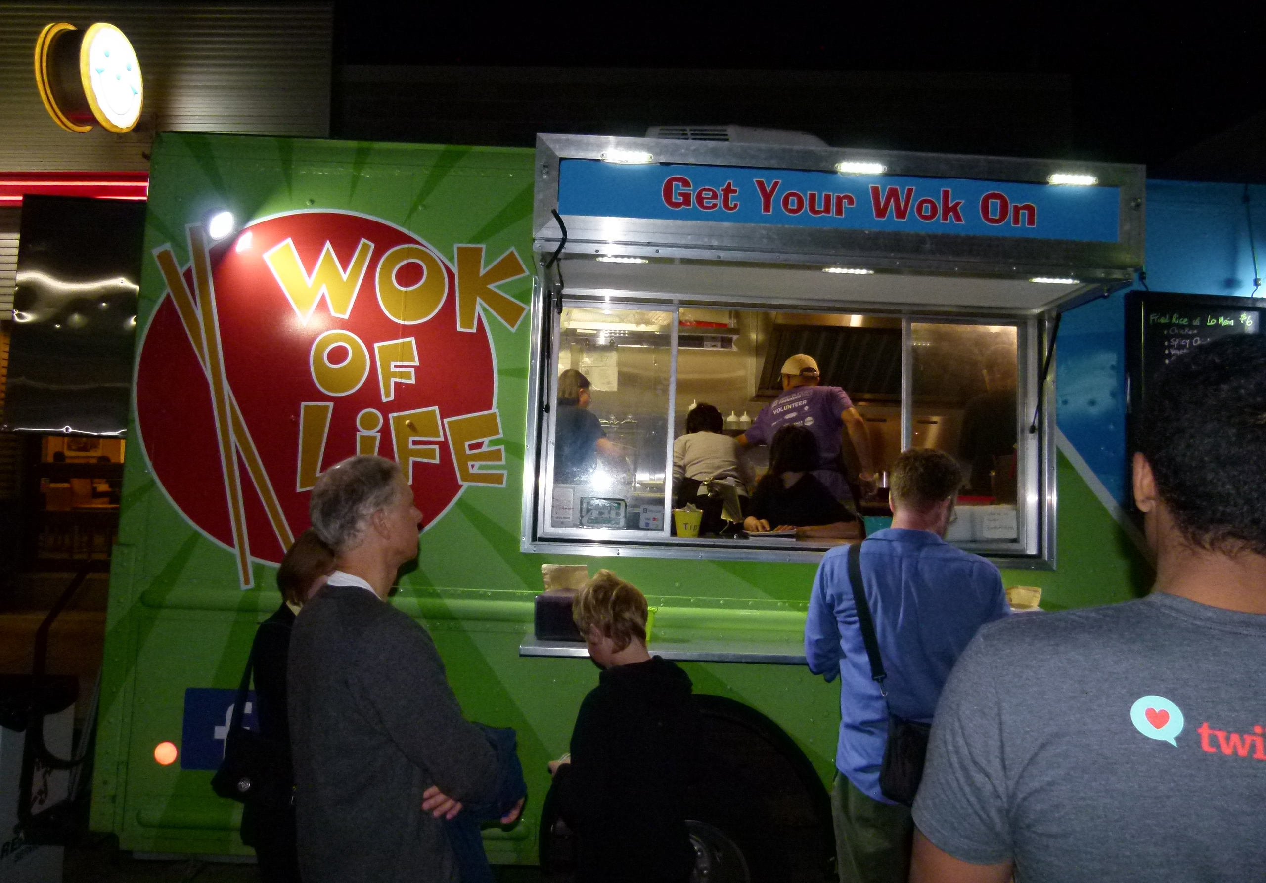 The crew at Wok of Life food truck rapidly preparing hungry patrons' orders as the Eat'n Park lighted Smiley Cookie sign illuminates from above.