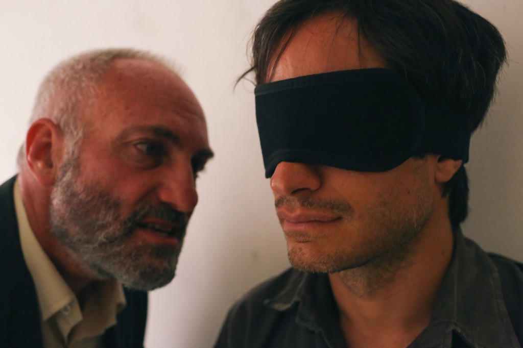 As Rosewater (Kim Bodnia, L) hammers away at the blindfolded Bahari (Gael Garcia Bernal), the question becomes: Who's really in the dark here? (Photo by Nasser Kalaji, courtesy of Open Road Films.)