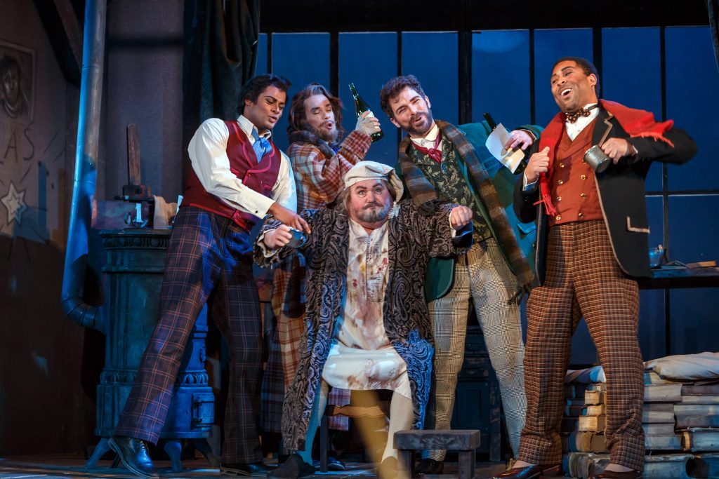 The operatically baffled guy in the center is basso buffo Kevin Glavin. He is the bohemians' landlord in 'La Boheme' at Pittsburgh Opera, and he's learning that the boys do not plan to pay the rent.