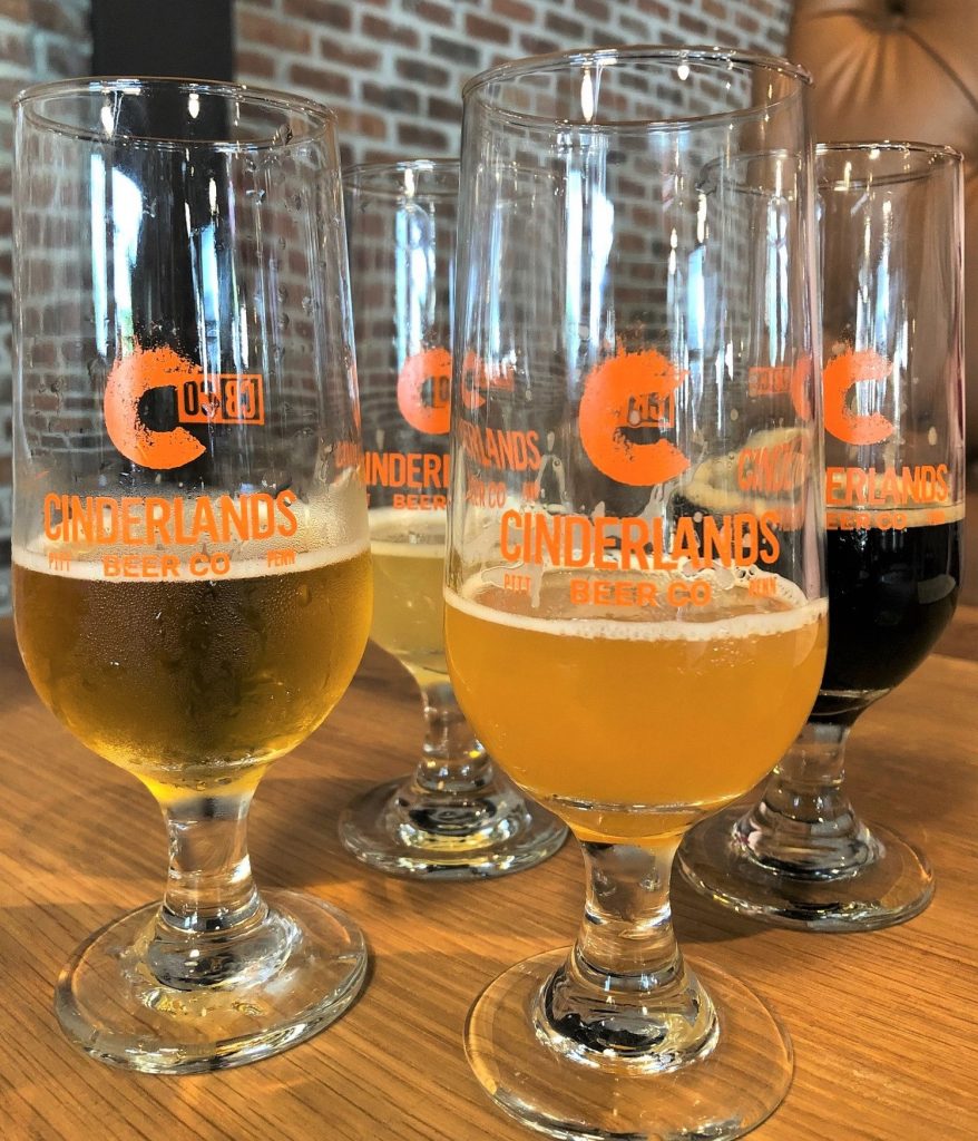A tasting array composed of (l. to r.) Tracks Again Unfiltered Pilsner, Grizzled Canary Grisette, Range of Light Double IPA, and Bougie Pajamas Tea Brown Ale.