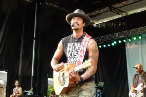 |Michael Franti poses with some fans for a photo before the concert.|Drummer Manas Itiene teams up with Franti on an upright drum.|Michael Franti spreading love and positive energy one tune at a time.|Franti engages the crowd during a fun jam.|A large crowd listens to the music.