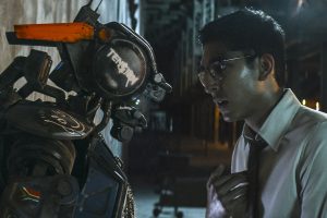 Deon (Dev Patel) boots up Chappie with the new program.|Chappie gets corrupted in "the hood."