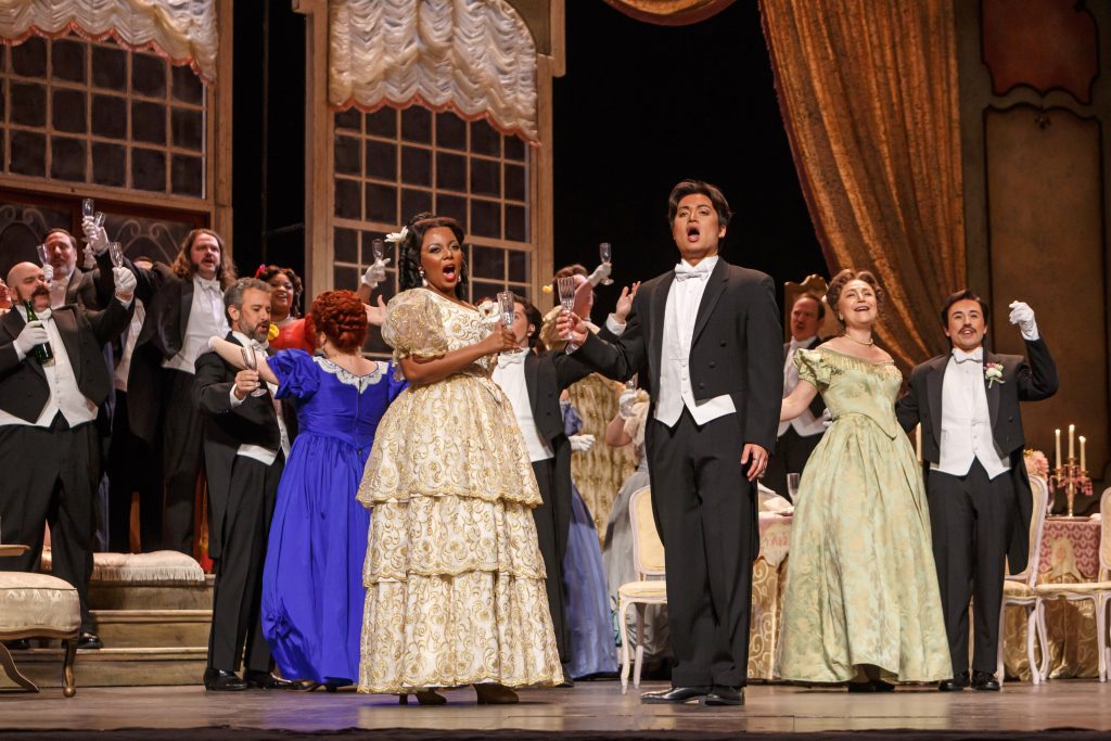 Violetta Valéry (Vuvu Mpofu), Alfredo Germont (Duke Kim)and the party guests make a toast to the sweetness of love. (Photo: David Bachman Photography for Pittsburgh Opera)