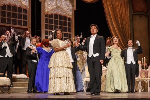 Violetta Valéry (Vuvu Mpofu) welcomes Alfredo Germont (Duke Kim) to join her in the drinking song 'Libiamo ne’lieti calici,' one of the more memorable choral elements of Verdi’s tragic opera.
