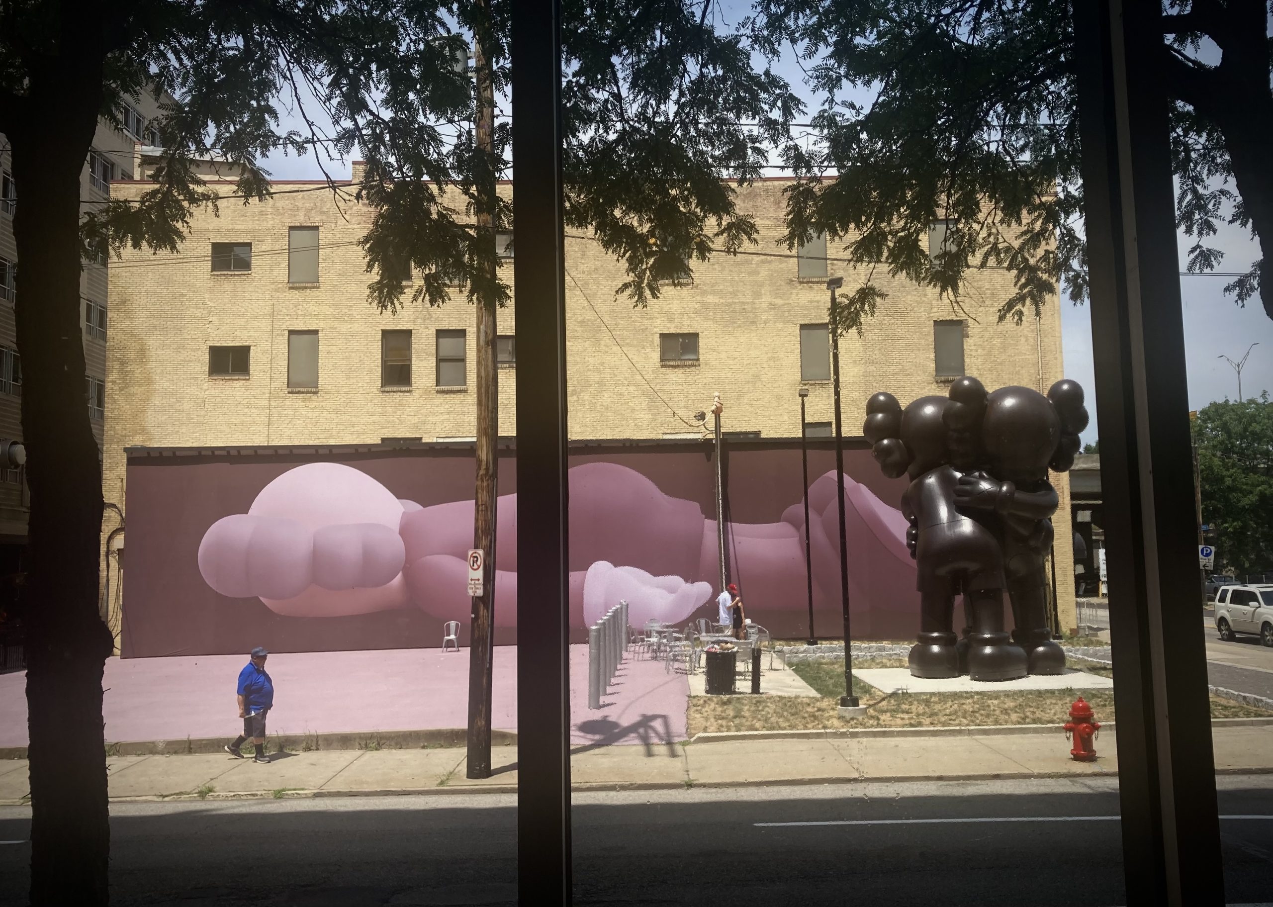 Across the street from The Warhol's lobby, the KAWS presence in Pittsburgh is announced by an immense installation. An outsized outdoor 'Companion' spans the wall of a building behind a towering version of the huggy sculpture 'Together.'