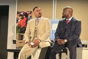 Partner and Tiger Woods fan Hicks (Rich Dickson) informs associate and mayoral candidate Harmond Wilks (Roosevelt Watts, Jr.) how important the game of golf can be in business.