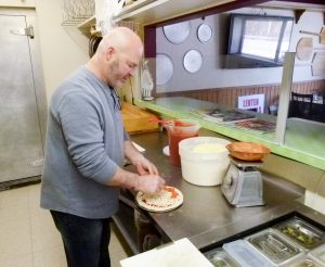 Owner Jim Hochendoner preparing a small pepperoni and cheese pizza.