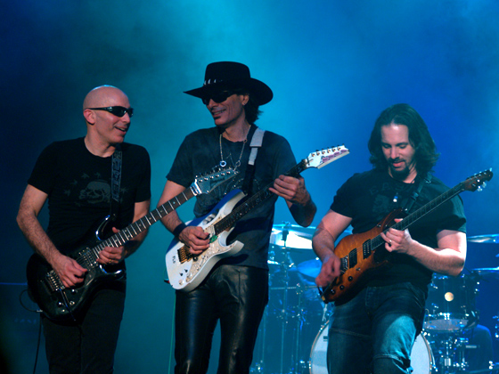 (l. to r.) Joe Satriani, Steve Vai, and John Petrucci on the 2006 G3 tour in Melbourne, Australia. Phil Collen of Def Leppard joins Satriani and Petrucci for this year's G3. Photo: Mandy Hall and Wikipedia.