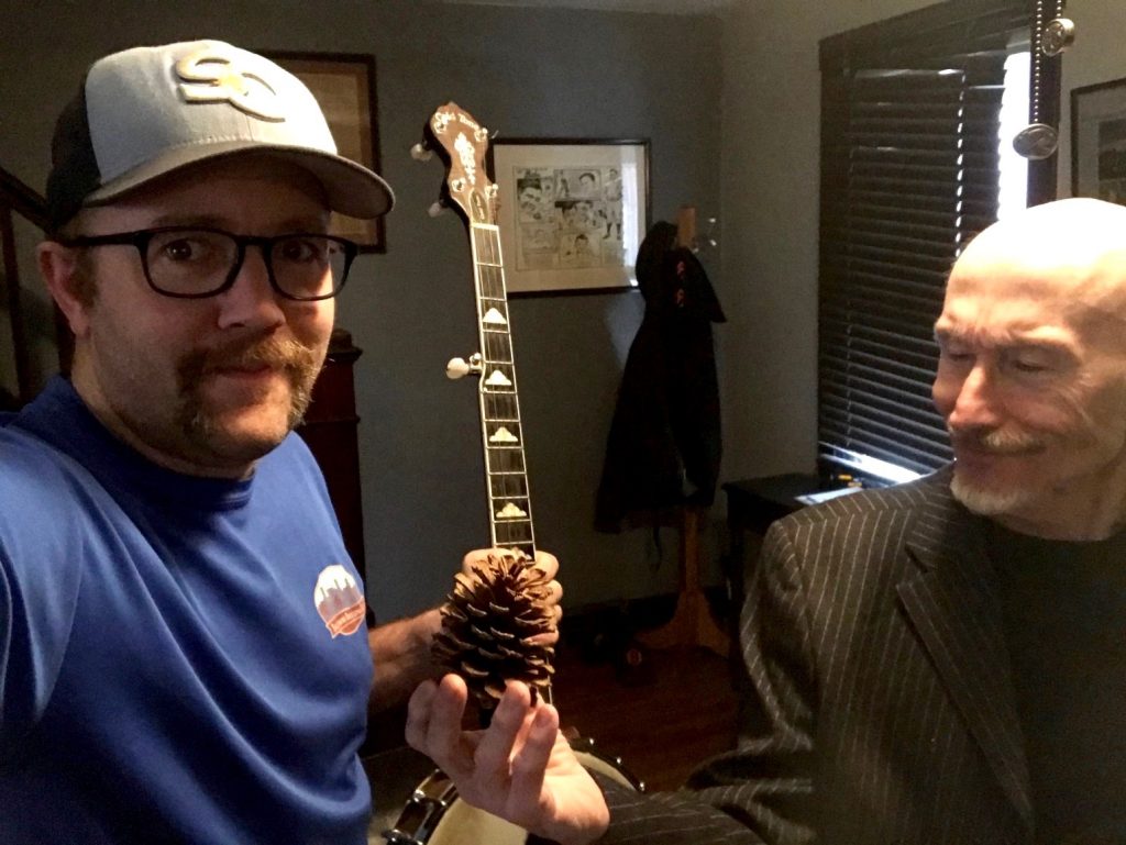 While Mike Vargo ponders the meaning of a pine cone, John W. Miller snaps a usie (a multi-person selfie) while also showcasing his banjo, when they are supposed to be rehearsing their 'Gun Talk' performance piece.