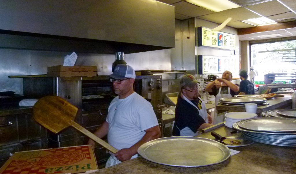 Ben Sciulli works the ovens while Michael Scheirer stretches pizza dough by tossing it in the air at Milano's. Shawn Stockdale works on an order between the two.
