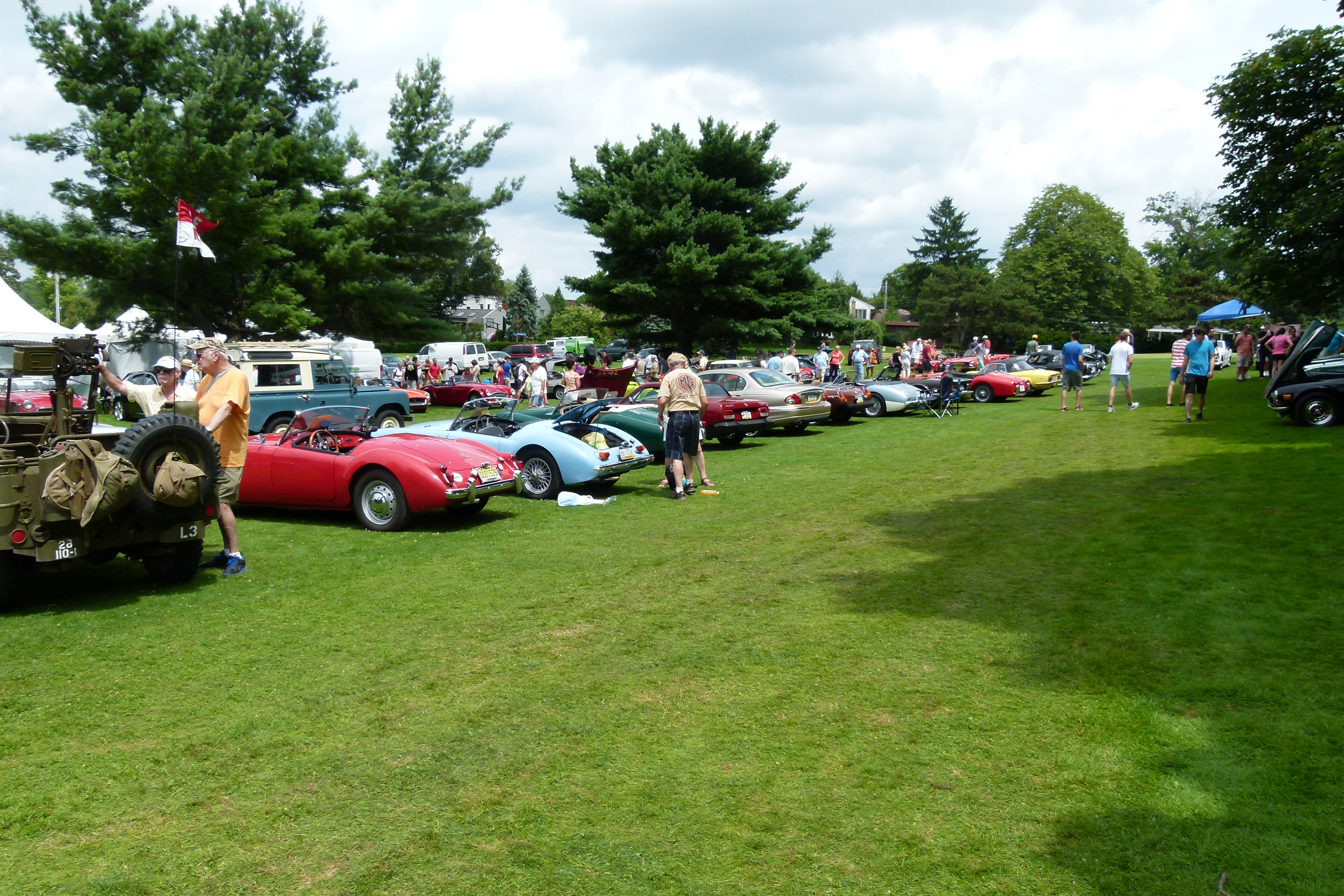 Many beautiful cars of different makes and models line the greens.