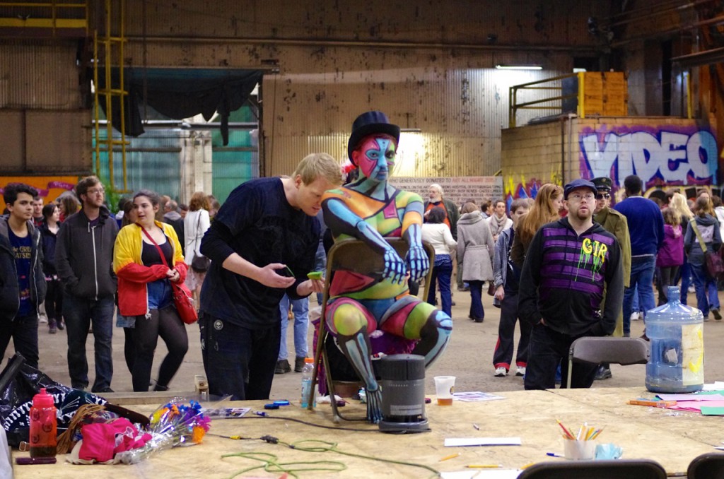 A bodypainter at work on a bright, eye-catching design.