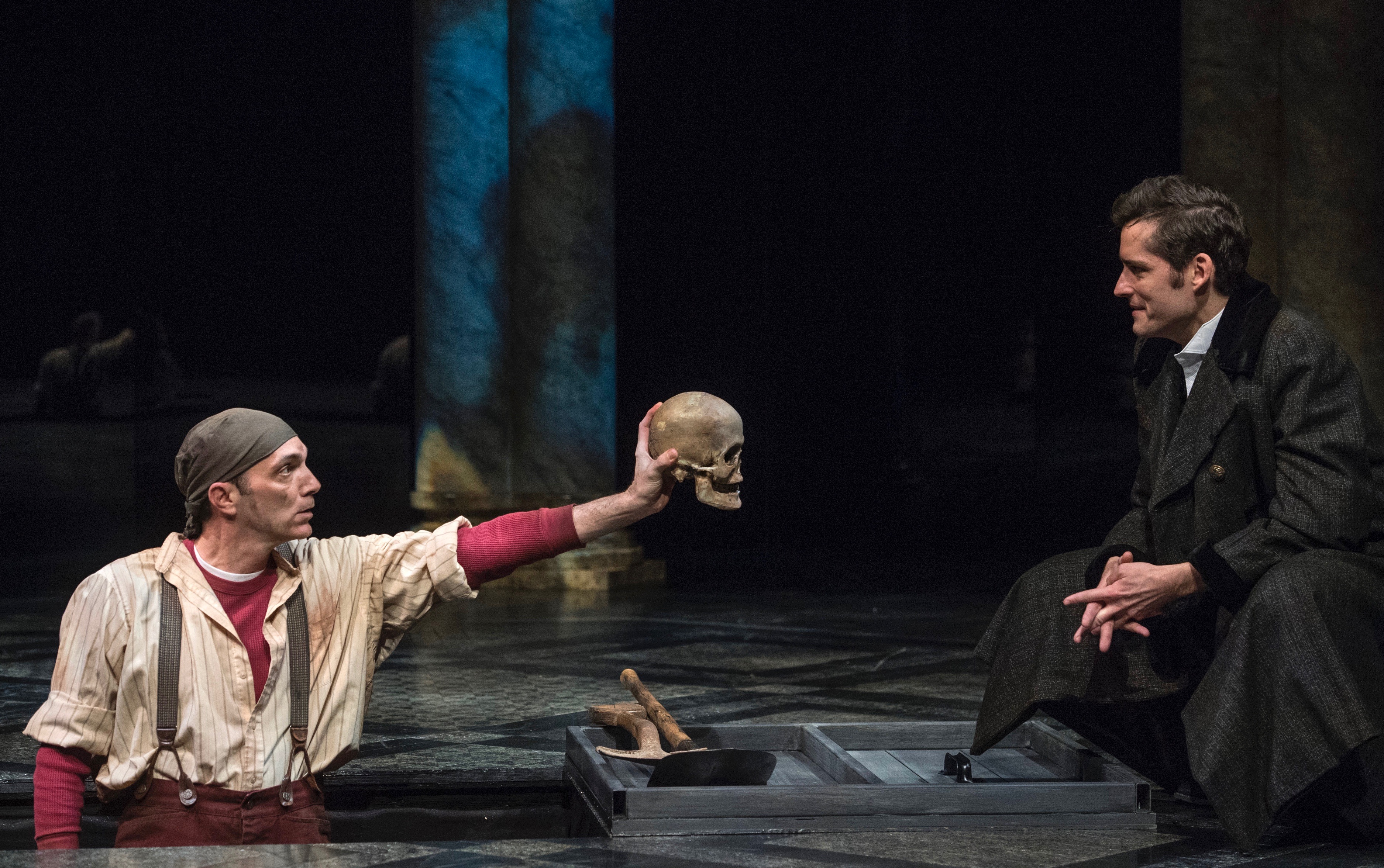 Viewing one skull should be enough for Hamlet, but he keeps going until 'the rest is silence.' Tony Bingham is the gravedigger and Matthew Arendt the Danish prince in The Public's 'Hamlet.'