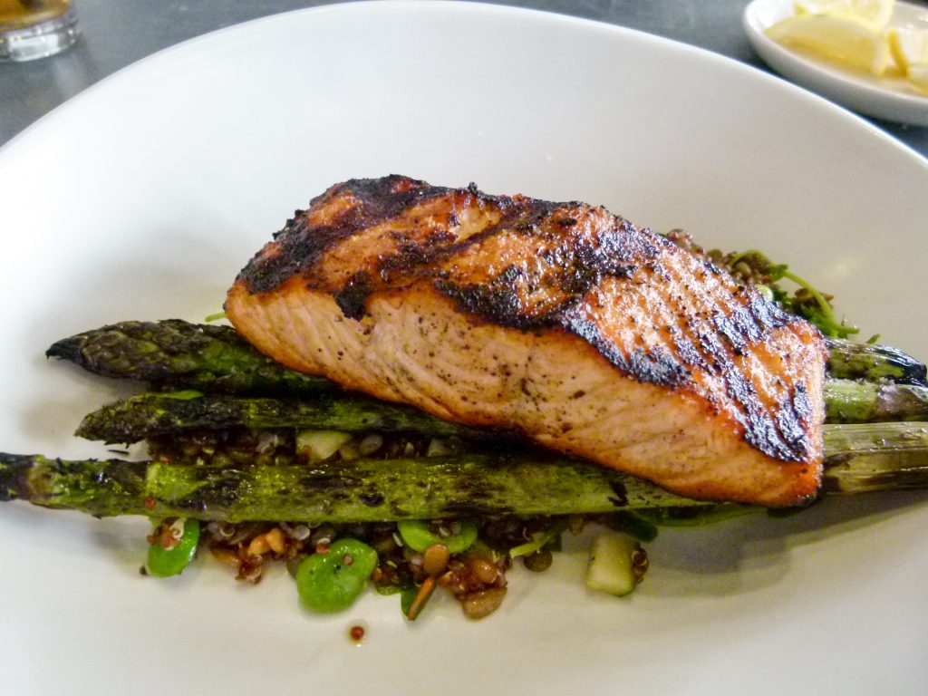 Wood grilled salmon nestled on a bed of asparagus spears.