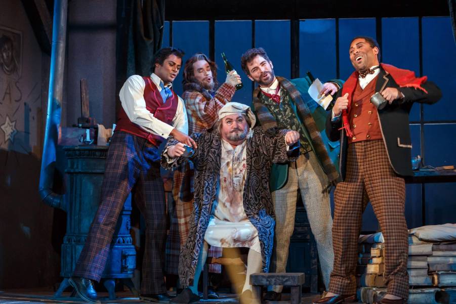 From Pittsburgh’s Opera’s 2019 production, the merry artists of La Boheme ply their landlord Benoit with drink in hopes he forgets to collect the rent. (Photo by David Bachman Photography.)